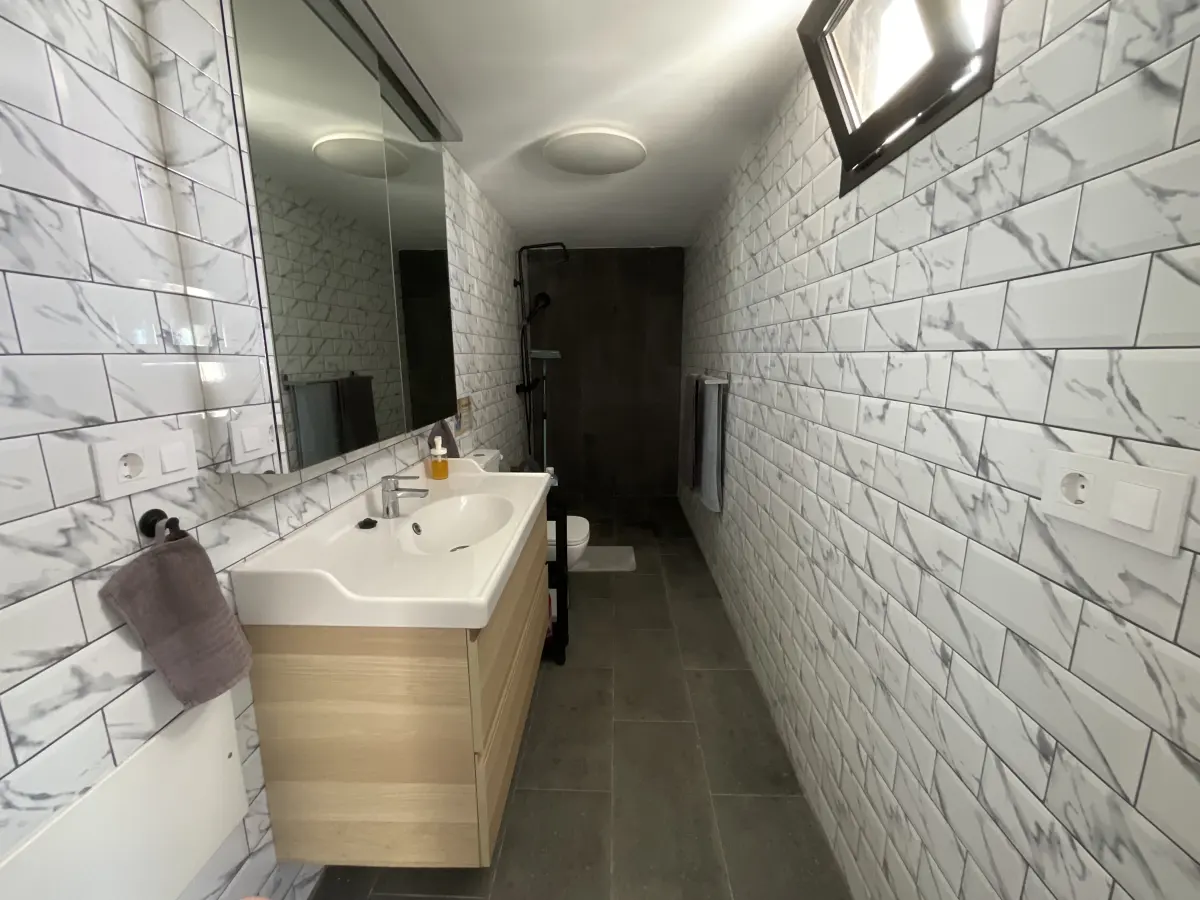 Salle de bain du F1, vasque sur meuble bois et douche à l'italienne