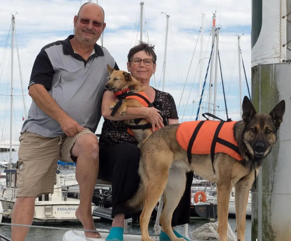 Éric et Corinne avec leurs deux chiens sur le pont d'un voilier