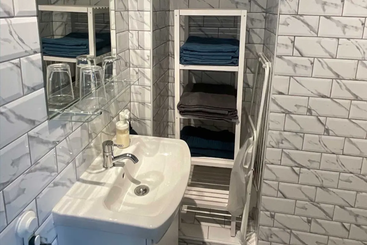 Salle de bain du Studio, lavabo, étagère à serviettes et douche à l'italienne