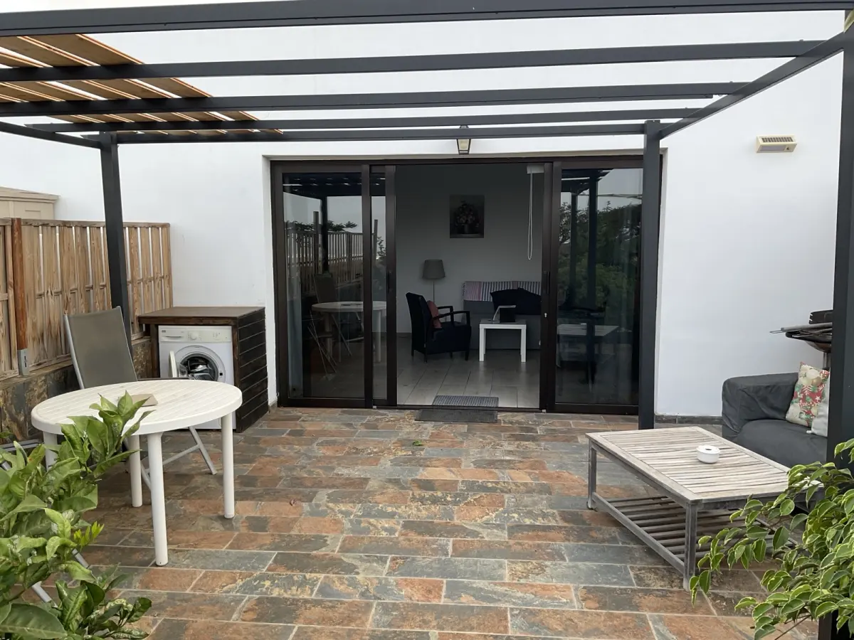 Terrasse du Studio sous pergola, salon de jardin et palissade en bois